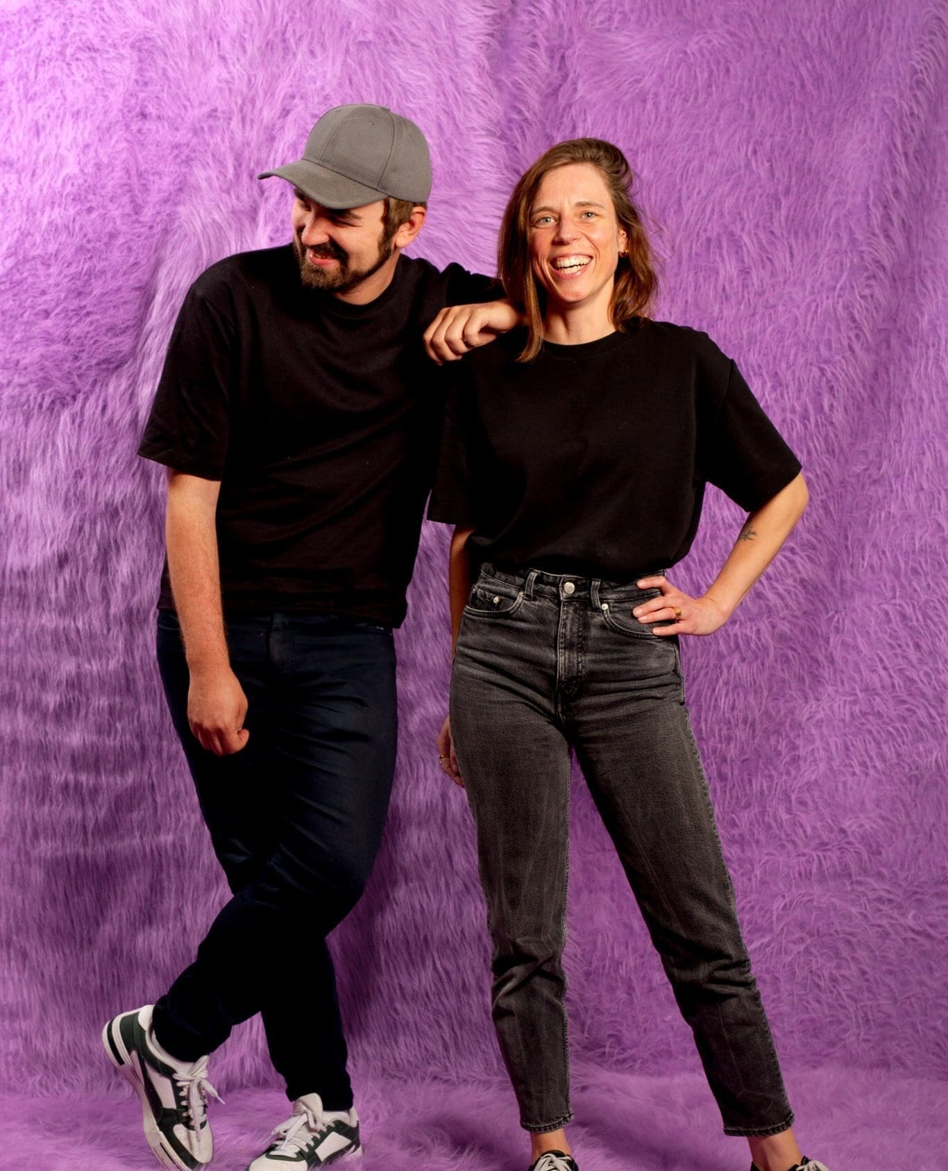 Matthew en Julie, teamleden bij June20, poseren lachend voor een paarse achtergrond
